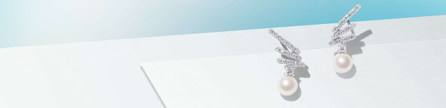 Yoko Ono London pearl and diamond drop earrings on a baby blue and light blue background